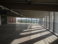 a corridor with many windows and signs in the sunlight behind them, with an empty walkway leading up to a window