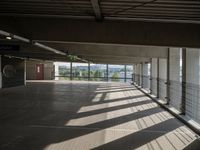 a corridor with many windows and signs in the sunlight behind them, with an empty walkway leading up to a window