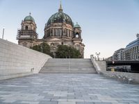 there is a large building with three domes and steps to it's left, with an empty concrete patio on the right