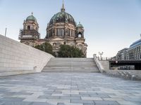 there is a large building with three domes and steps to it's left, with an empty concrete patio on the right