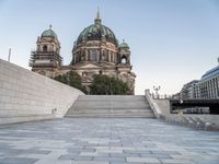 there is a large building with three domes and steps to it's left, with an empty concrete patio on the right