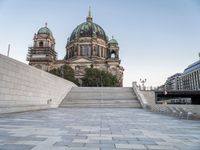 there is a large building with three domes and steps to it's left, with an empty concrete patio on the right