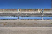 concrete structure with a body of water reflecting it in the road near a large building