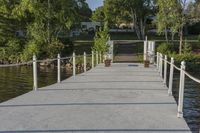 a dock that is connected to a pond and some trees behind it with a white fence