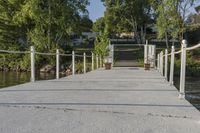 a dock that is connected to a pond and some trees behind it with a white fence