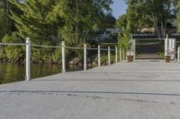 a dock that is connected to a pond and some trees behind it with a white fence