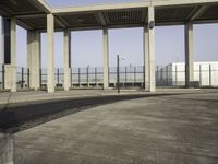 the empty parking lot is filled with vehicles and concrete pillars with shadows of columns on the floor