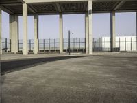 the empty parking lot is filled with vehicles and concrete pillars with shadows of columns on the floor