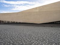 a view from outside of a building on a stone road area with a light stone paved area behind it