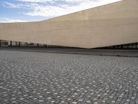 a view from outside of a building on a stone road area with a light stone paved area behind it