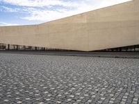 a view from outside of a building on a stone road area with a light stone paved area behind it