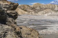 the landscape is barren, and blue sky has clouds in it and rocks on each side