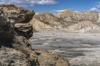 the landscape is barren, and blue sky has clouds in it and rocks on each side