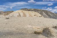 a red fire hydrant stands in an arid desert area with cliffs behind it,