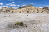 an empty desert with mountains and dry ground in the distance and clouds in the sky