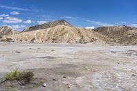 an empty desert with mountains and dry ground in the distance and clouds in the sky