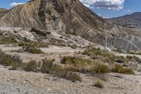 the top of a hill surrounded by hills and shrubs in the desert, and road with steeps