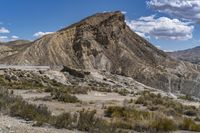 the top of a hill surrounded by hills and shrubs in the desert, and road with steeps