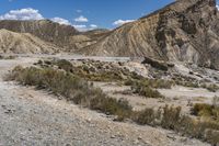 the top of a hill surrounded by hills and shrubs in the desert, and road with steeps