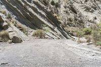 a motorcycle is traveling down an empty dirt road in a mountainous area with steep cliffs