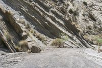 a motorcycle is traveling down an empty dirt road in a mountainous area with steep cliffs