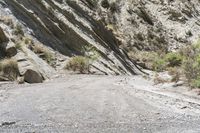 a motorcycle is traveling down an empty dirt road in a mountainous area with steep cliffs