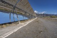 a large array of mirrors in a desert landscape with a fence on each side and dirt roads