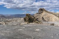 mountains with desert with rocks and dirt all around in a plain of land under clouds