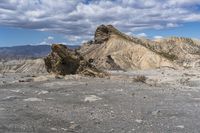 mountains with desert with rocks and dirt all around in a plain of land under clouds