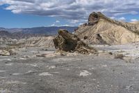 mountains with desert with rocks and dirt all around in a plain of land under clouds