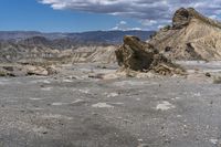 mountains with desert with rocks and dirt all around in a plain of land under clouds