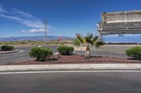 an empty street next to a stop sign on top of a hill by a lake