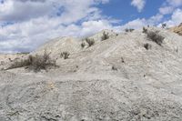 a large mound of dirt and vegetation with sky in the background and white clouds above