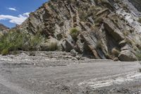 there is a motorcycle on a mountain side next to rocks and shrubs and vegetation at this stage of the ride