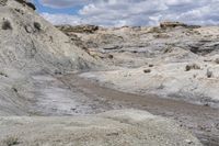 a muddy path and some dirt and rocks under clouds on the sky with blue skies