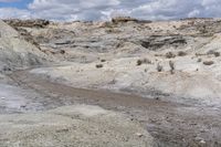 a muddy path and some dirt and rocks under clouds on the sky with blue skies