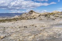 rocky landscape with rock formations and mountains in the background on a sunny day, showing the ground and dry grass