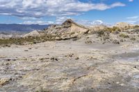 rocky landscape with rock formations and mountains in the background on a sunny day, showing the ground and dry grass