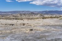 rocky landscape with rock formations and mountains in the background on a sunny day, showing the ground and dry grass