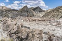 an area of rocky rocks in front of a partly clouded sky and blue skies, with green shrubs