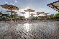 a group of tables sitting on top of a wooden deck with umbrellas and tables under them