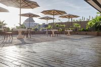 a group of tables sitting on top of a wooden deck with umbrellas and tables under them