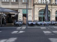 the tables outside the restaurant are covered with white table cloths and chairs set outside the building