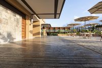 this is a patio with many tables and umbrellas outside on a wooden decking walkway