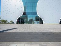 a white elephant sculpture sits in front of a large building with a large yellow bear