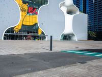 a woman on a phone sitting in front of a large white sculpture in the city