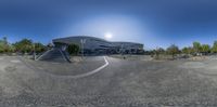 view of empty parking lot and modern building as seen through fish eye lens on bright day