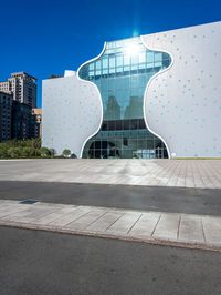 the white building has a glass front and a curved side on it's side