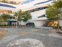 a parking lot with several trees growing in the middle of it and a building on the far corner