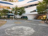 a parking lot with several trees growing in the middle of it and a building on the far corner